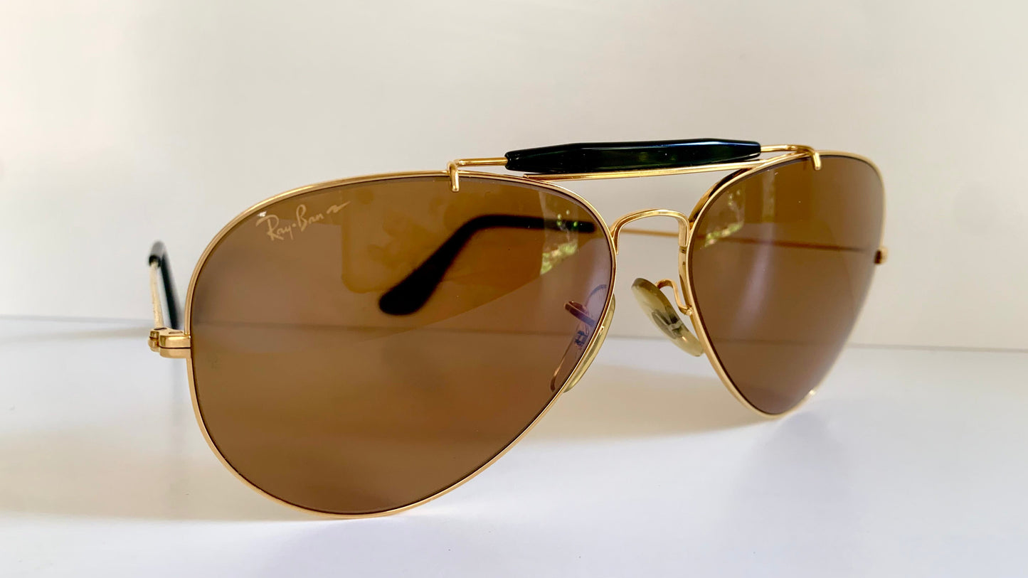 Ray Ban Chromax outdoorsman Gold-framed sunglasses with golden lenses on a white background,