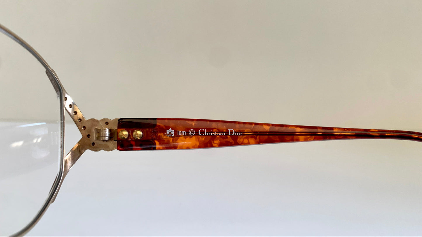 Close-up of a tortoiseshell and silver Christian Dior eyeglass frame on a white background