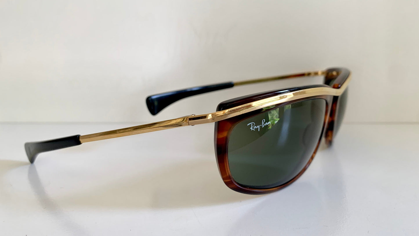 Ray-Ban sunglasses with gold frame and tortoiseshell arms on a white background