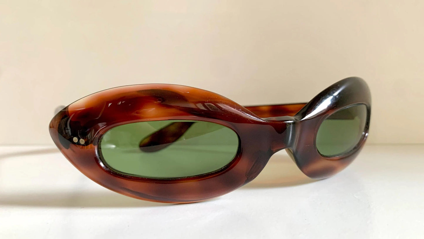 Sunglasses with tortoiseshell frame and green lenses on a beige background