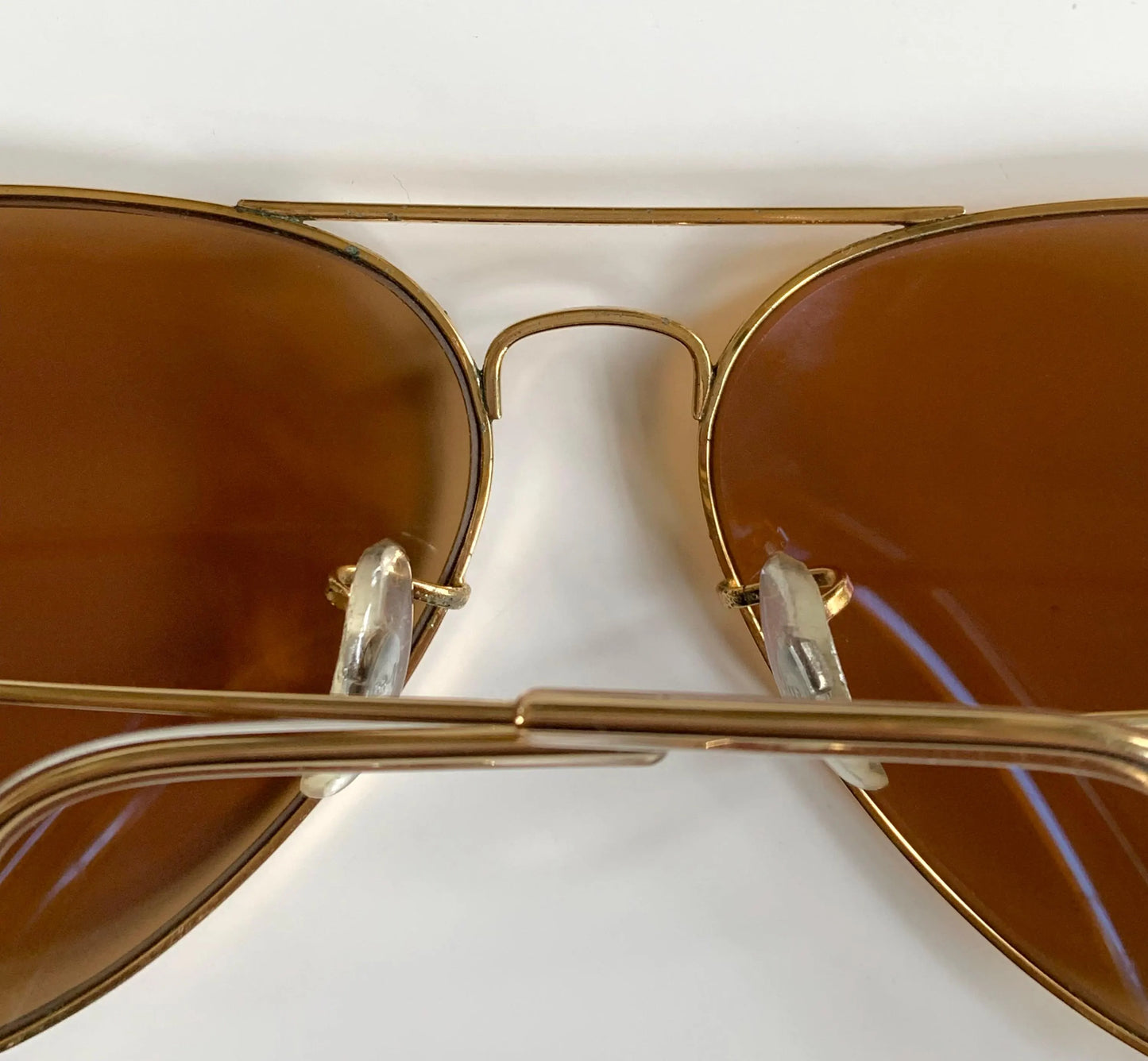 Gold-framed sunglasses with brown lenses on a white background