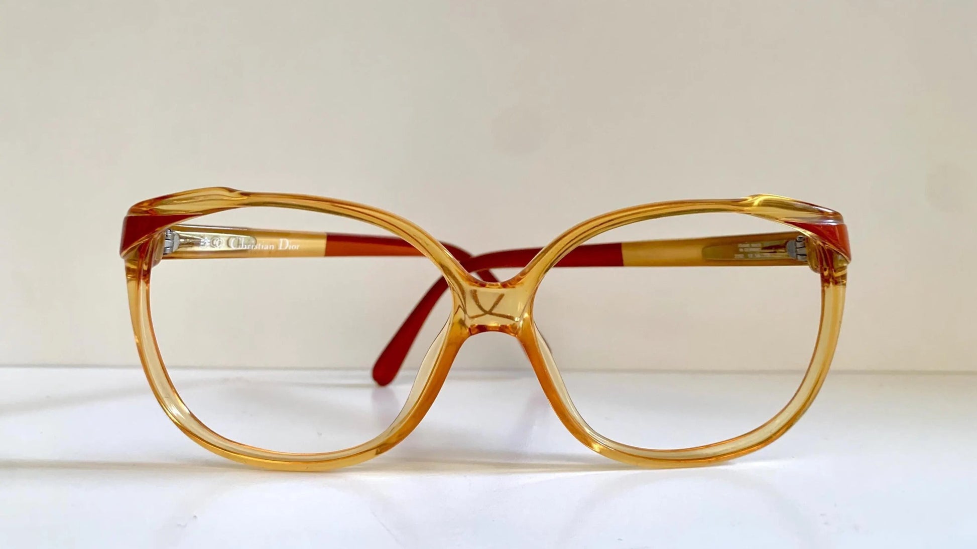Vintage Christian Dior eyeglasses with a yellow frame and red accents on a light background