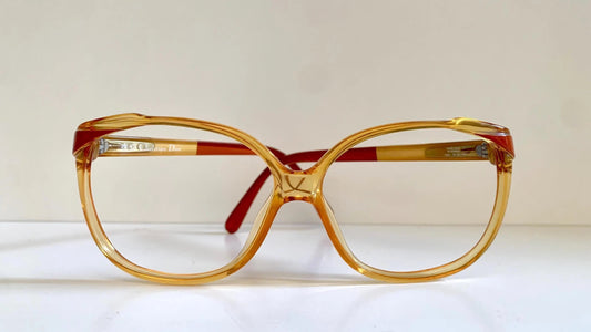 Vintage Christian Dior eyeglasses with a yellow frame and red accents on a light background