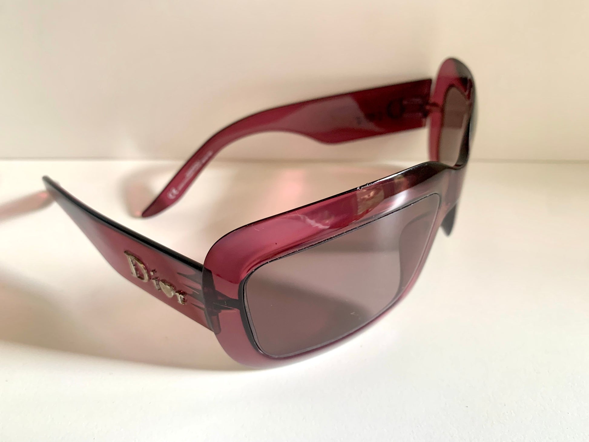 Dior sunglasses with a pink frame and dark lenses on a white background
