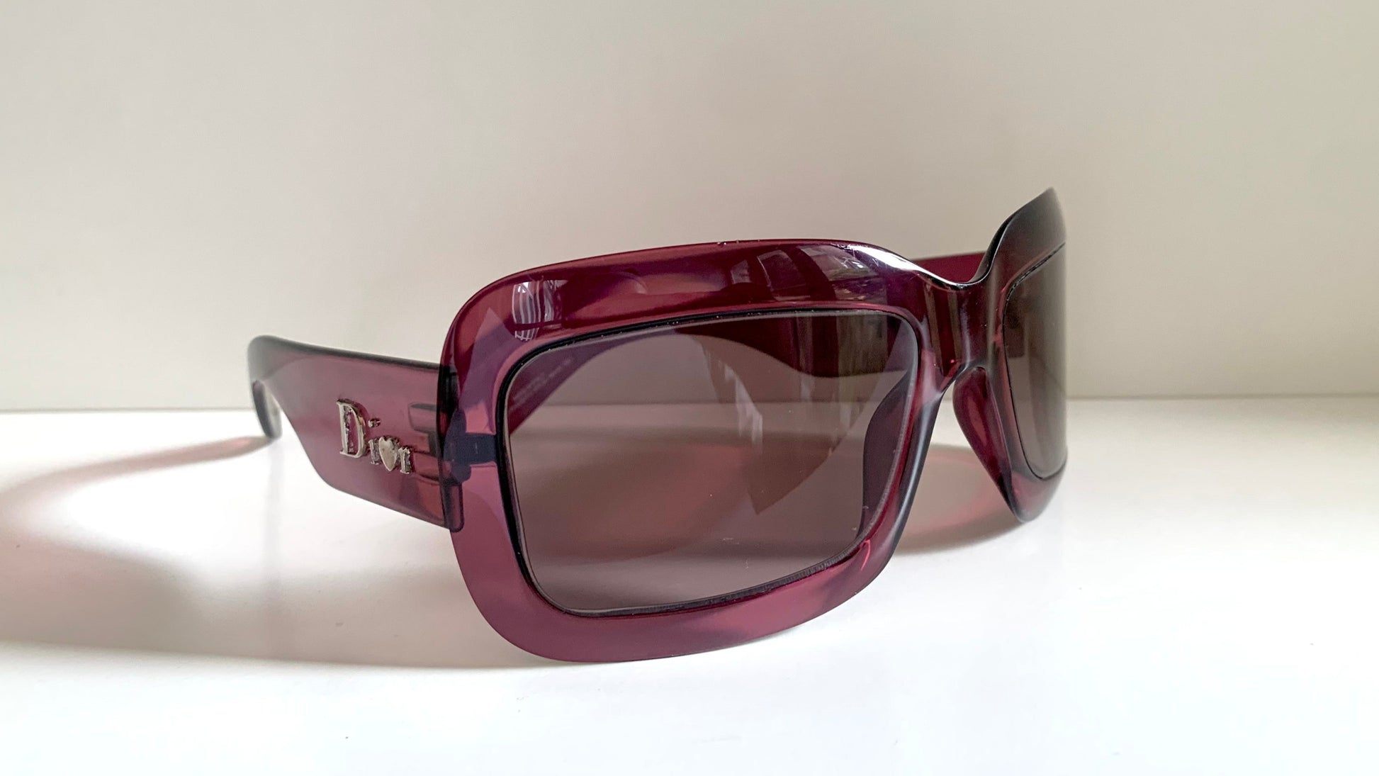 Dior sunglasses with a pink frame and dark lenses on a white background