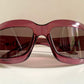 Dior sunglasses with a pink frame and dark lenses on a white background