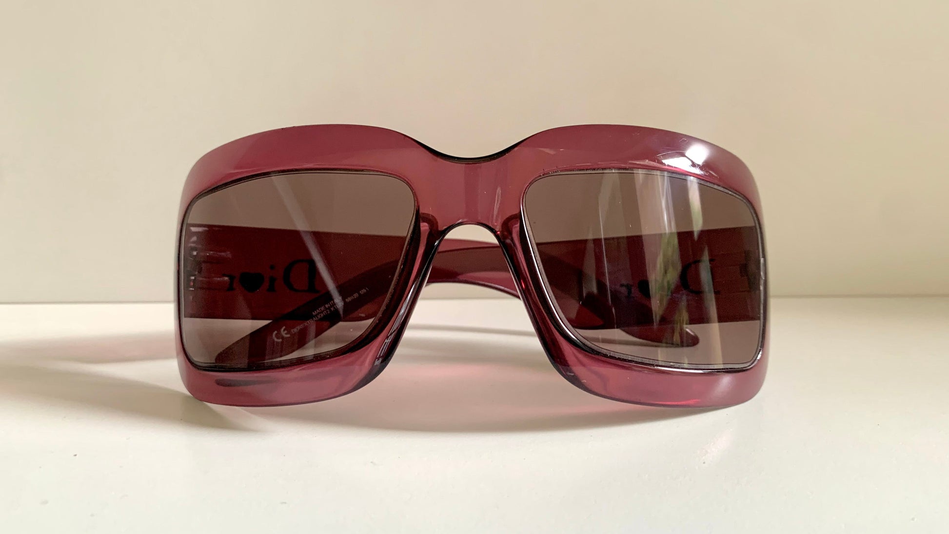 Dior sunglasses with a pink frame and dark lenses on a white background