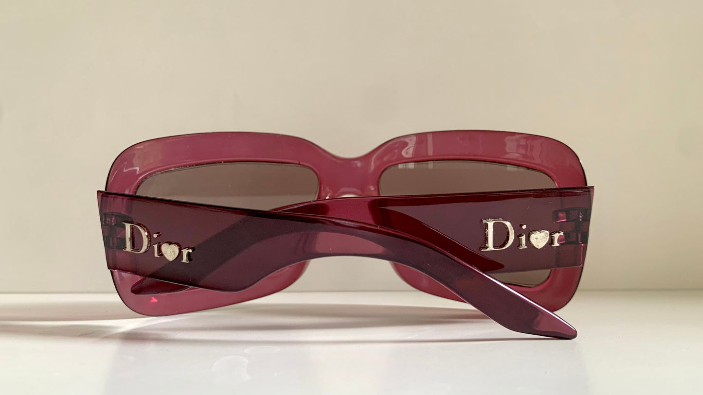 Dior sunglasses with a pink frame and dark lenses on a white background