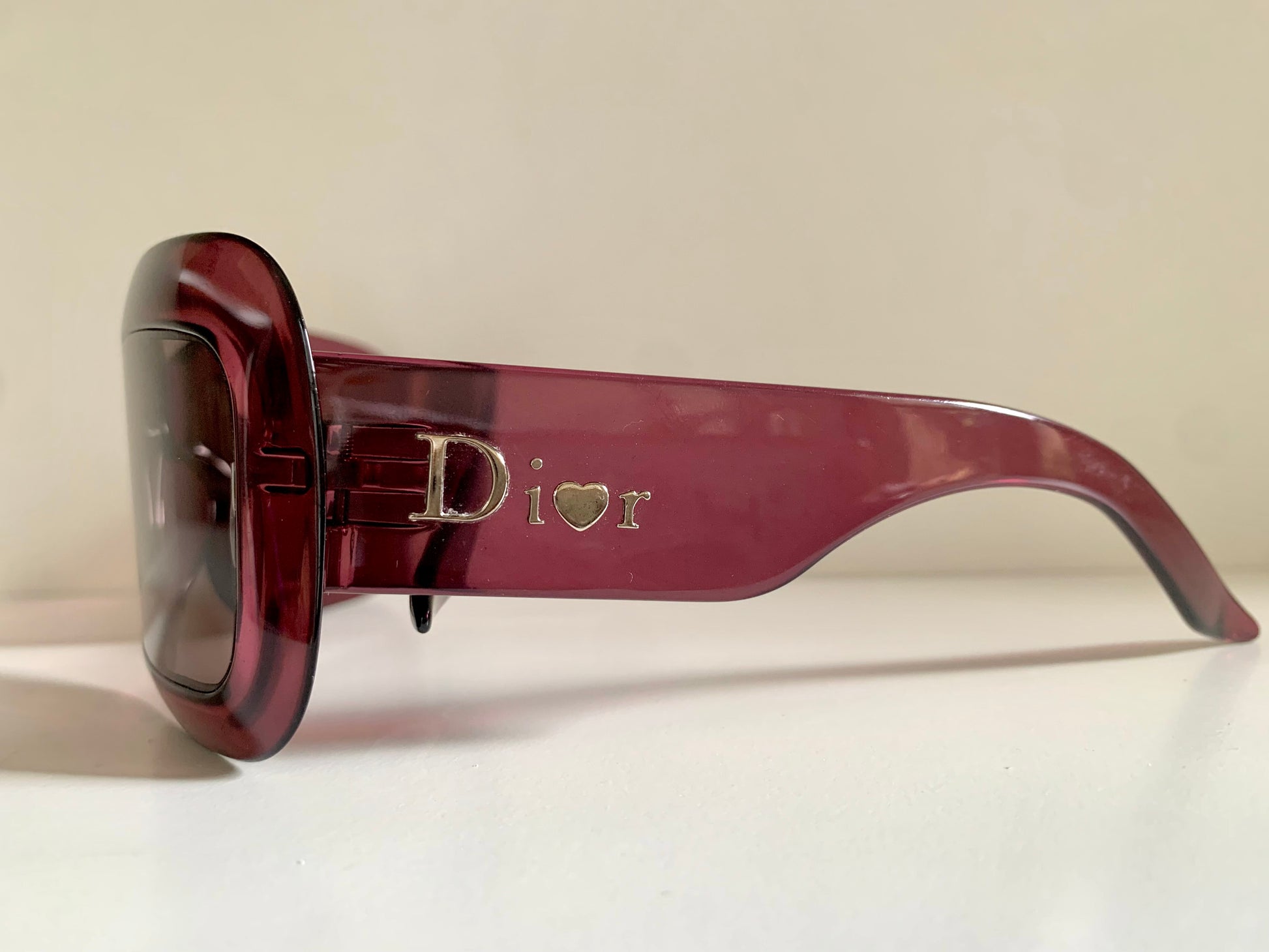 Dior sunglasses with a pink frame and dark lenses on a white background