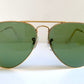 Aviator sunglasses with gold frame and green lenses on a white background
