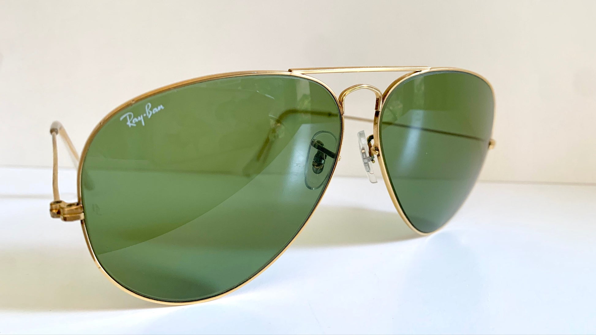 Aviator sunglasses with gold frame and green lenses on a white background