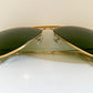Gold-framed sunglasses with green lenses on a white background