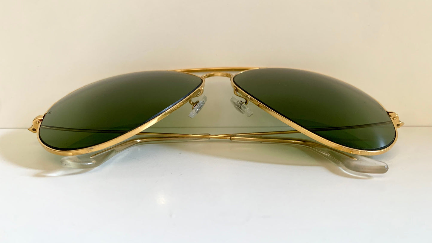 Gold-framed sunglasses with green lenses on a white background