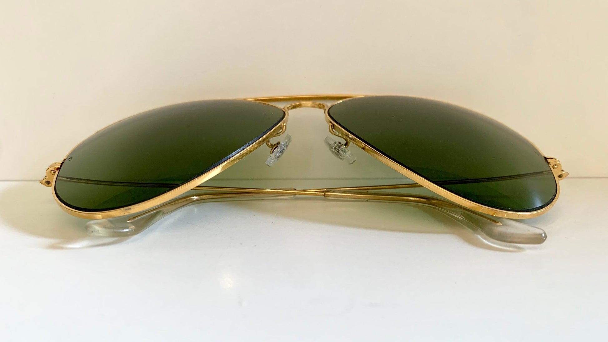 Gold-framed sunglasses with green lenses on a white background