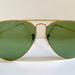 Aviator sunglasses with gold frame and green lenses on a white background