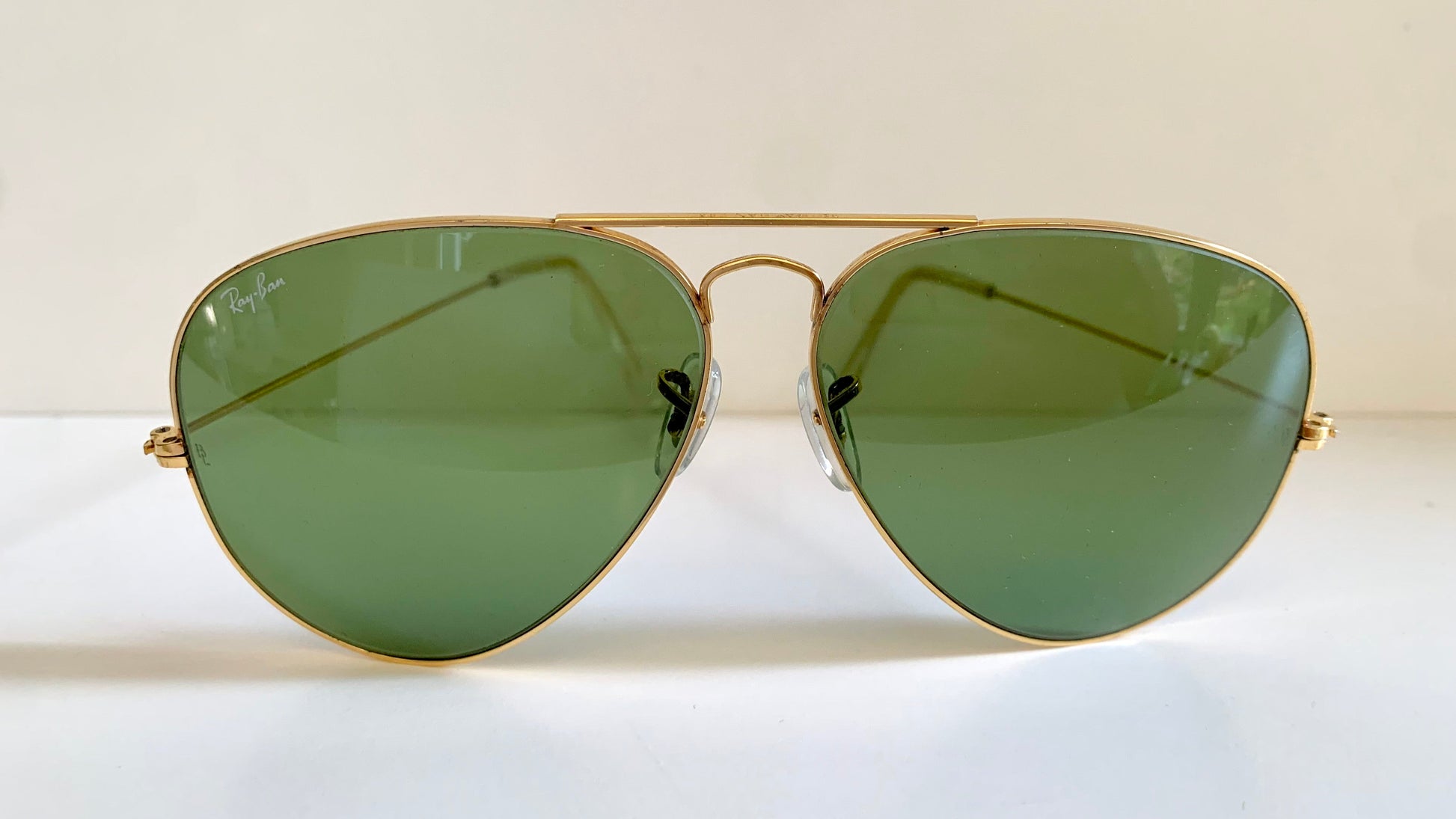 Aviator sunglasses with gold frame and green lenses on a white background