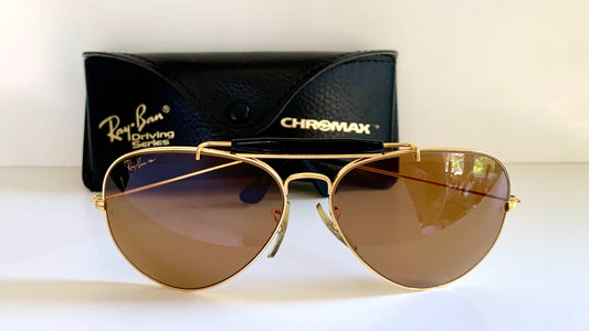Ray Ban Chromax outdoorsman Gold-framed sunglasses with golden lenses on a white background, accompanied by a black case.