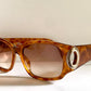 Brown tortoiseshell sunglasses with a Dior logo on a white background