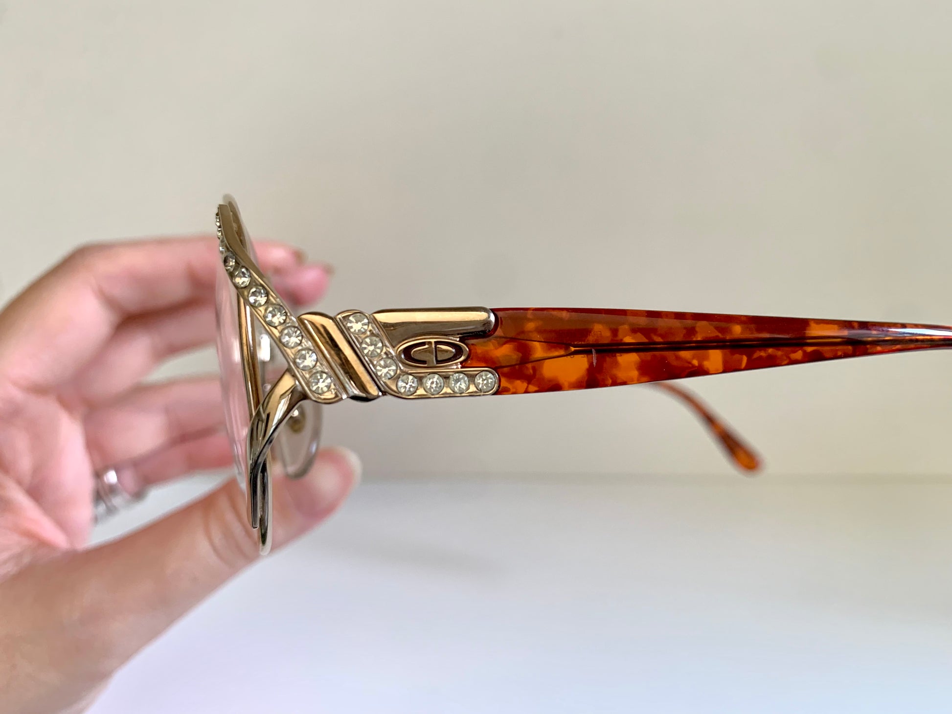 Pair of Christian Dior eyeglasses on a white surface with a beige background