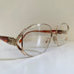 Silver-rimmed eyeglasses with decorative details on a white surface