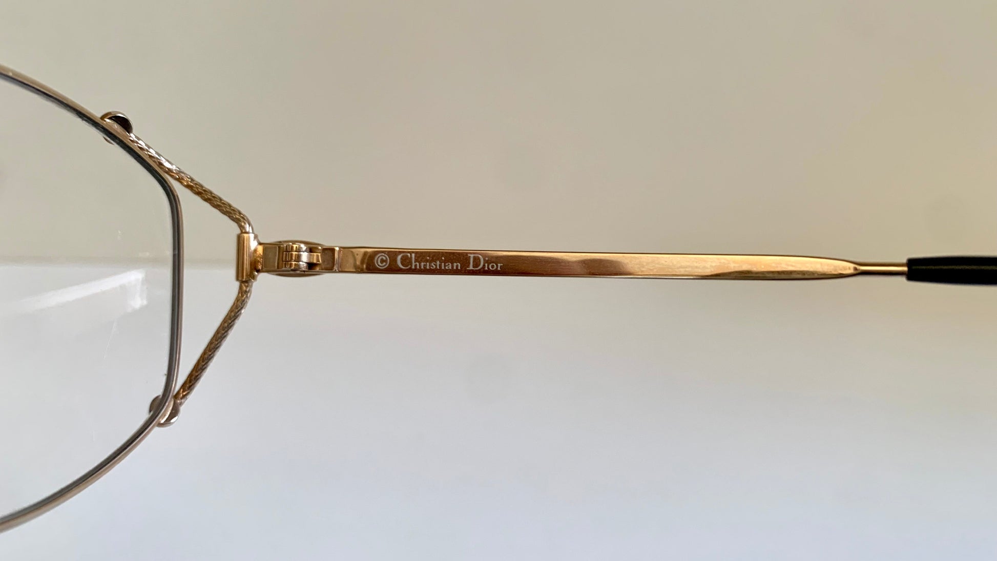 Gold-framed eyeglasses with 'Christian Dior' branding on a light background
