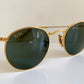 Ray Ban round sunglasses with gold frame and green lenses on a white background