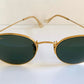 Gold-framed sunglasses with green lenses on a white background