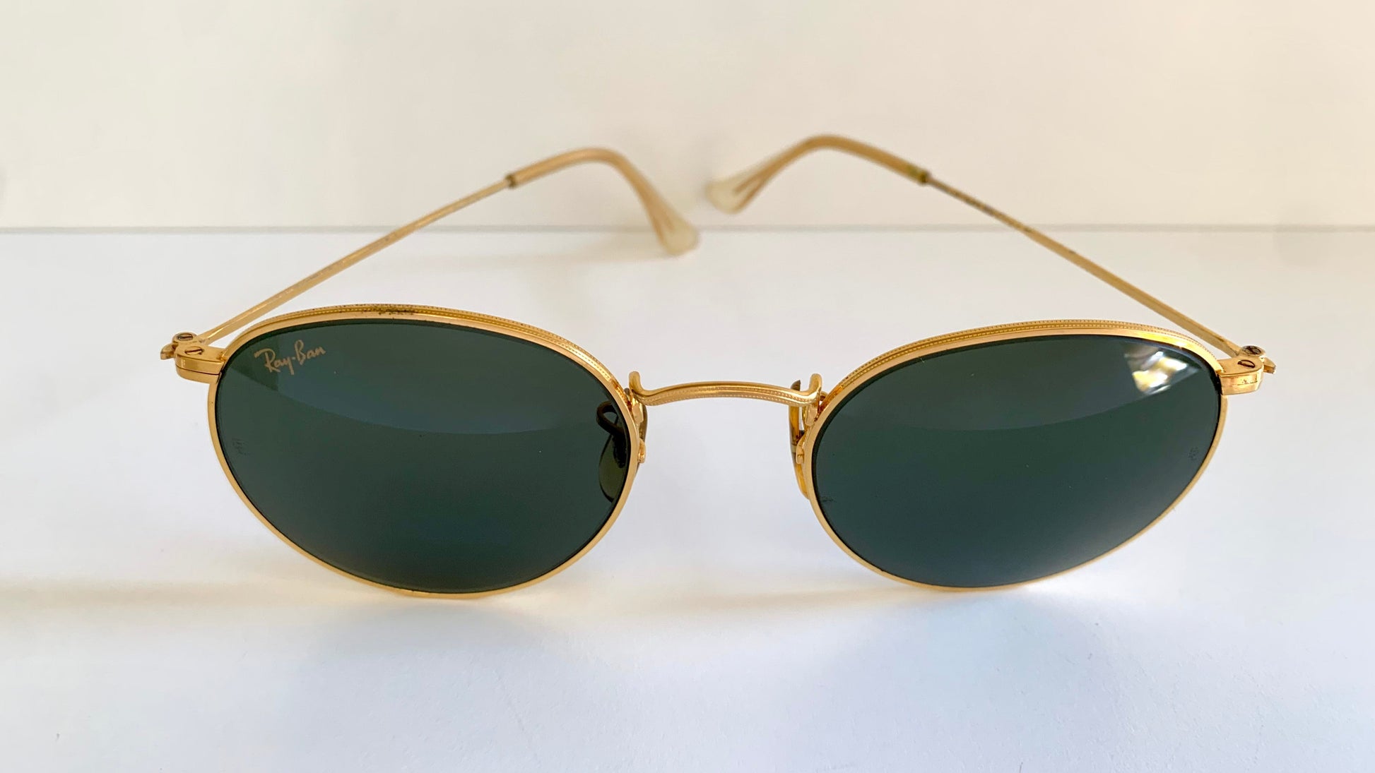 Gold-framed sunglasses with green lenses on a white background