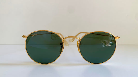 Ray Ban round sunglasses with gold frame and green lenses on a white background