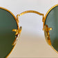 Gold-framed sunglasses with green lenses on a white background