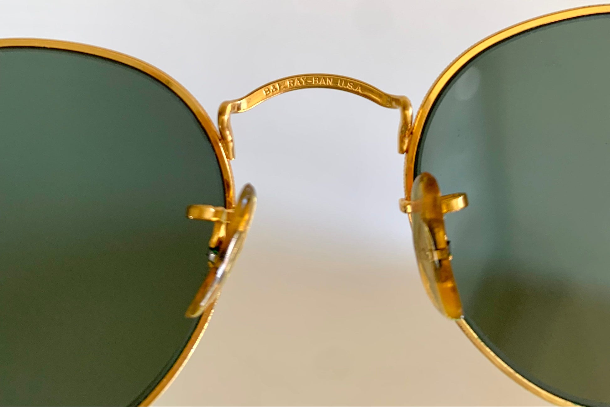 Gold-framed sunglasses with green lenses on a white background