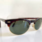 Sunglasses with a tortoiseshell frame and dark lenses on a white background