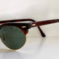 Sunglasses with brown frame and green lenses on a white background