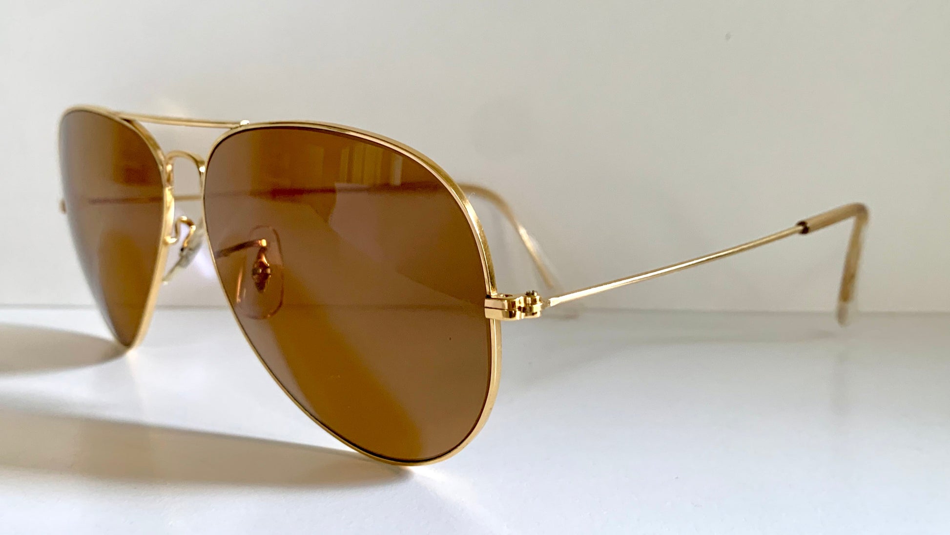 Ray Ban Chromax Gold-framed sunglasses with brown lenses on a white background