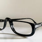 Black eyeglasses on a white surface with a light gray background