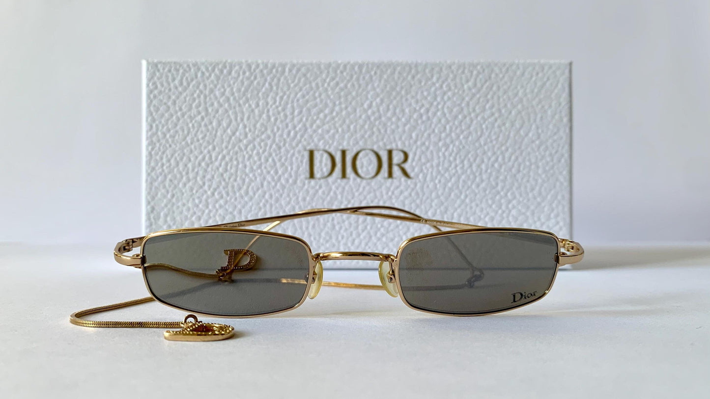 Gold-framed sunglasses with 'Dior' branding on a white background