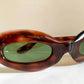 Sunglasses with tortoiseshell frame and green lenses on a beige background