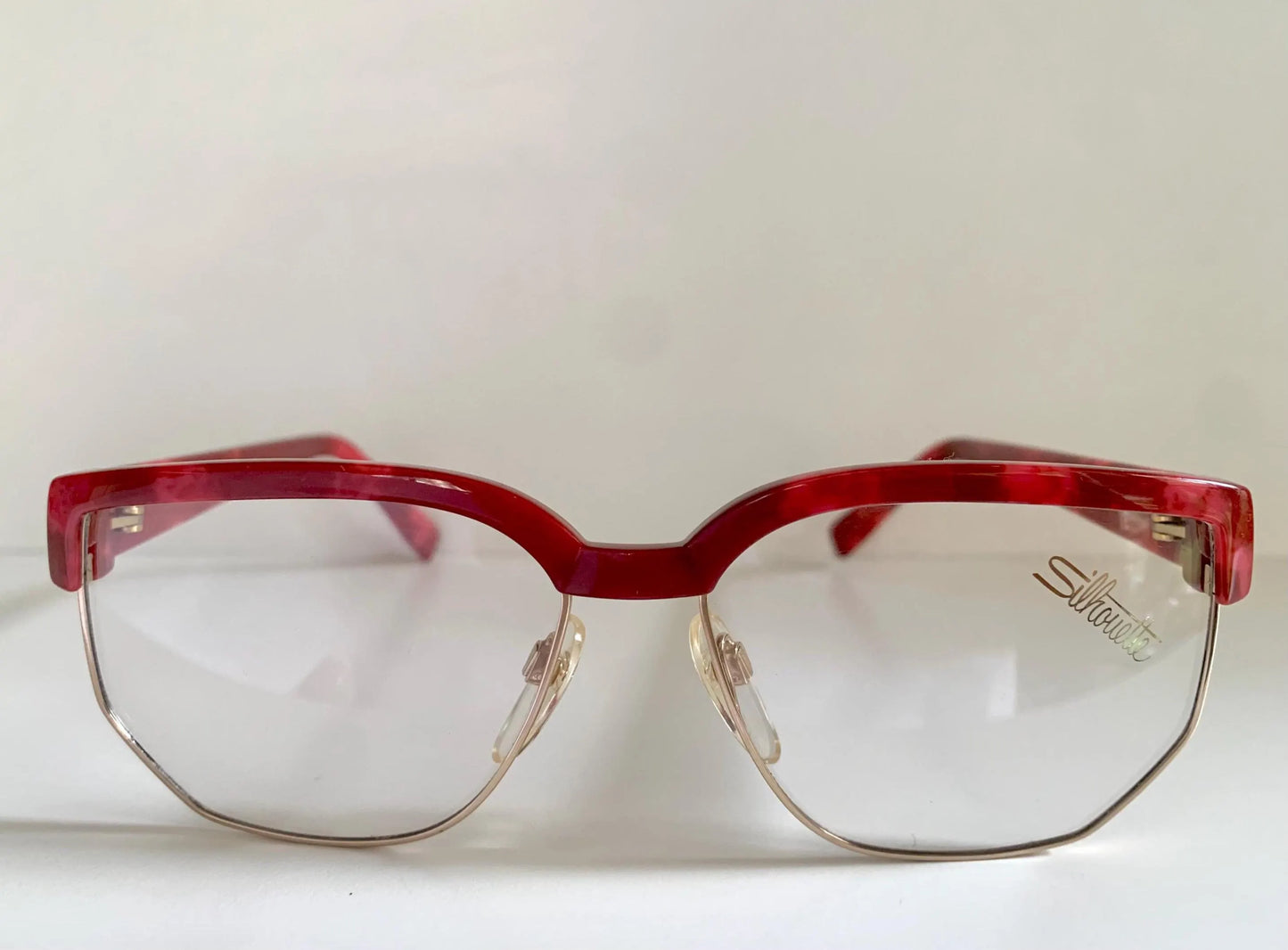 Red eyeglasses with a visible brand logo on a white background